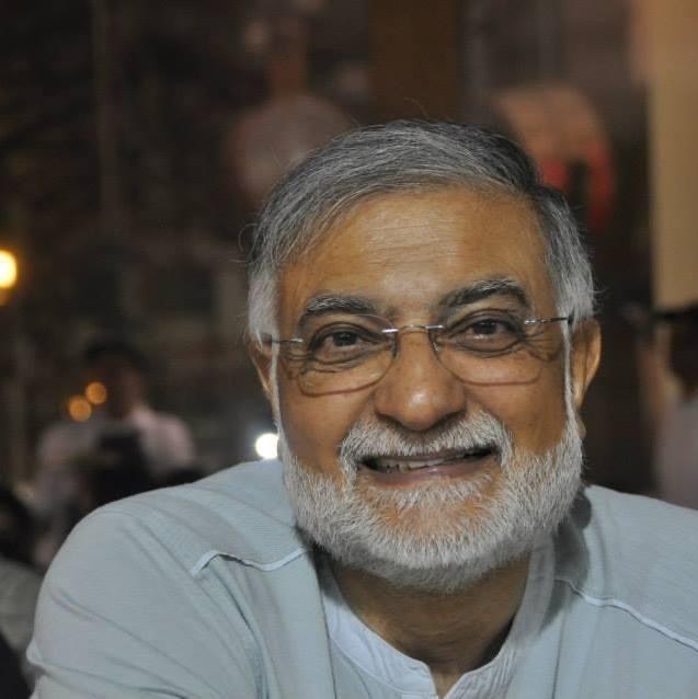 Portrait of Ashok Kumar Chadha, smiling, with grey hair, a white beard and rimless glasses.